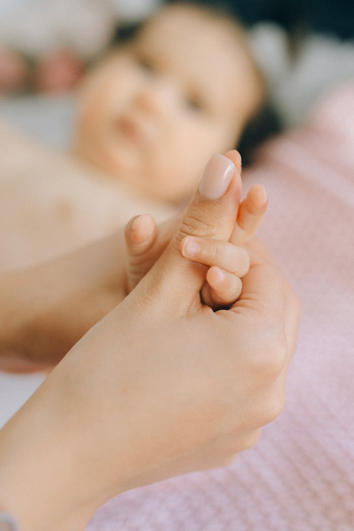 why-choose-us-02 A close-up of a mother gently holding her baby's hand, symbolizing love and care.
